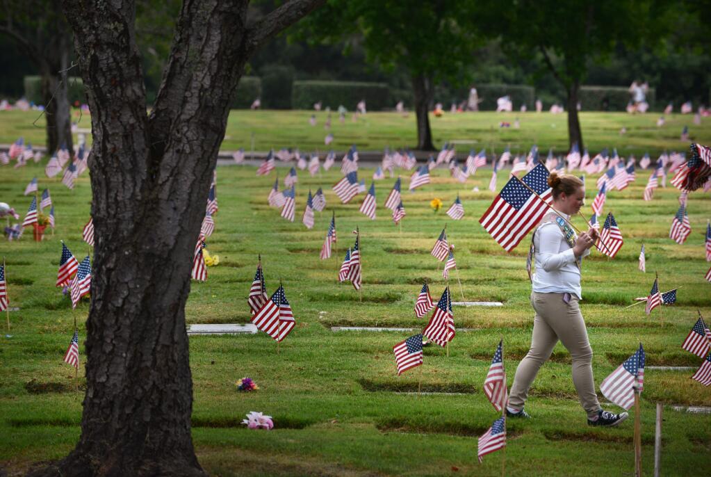 Kinsley Sackett, a Girl Scout, planting flags on the graves of veterans at Santa Rosa Memorial Park Cemetery (ERICK CASTRO / For The Press Democrat, 2017)