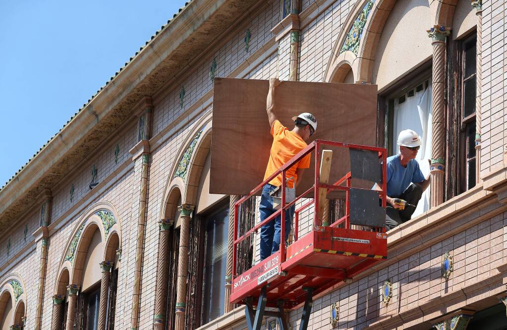 Kyle Williams and Liam Rooney work on boarding up a second-story window on a First Street building in Napa on Monday, Aug. 25, 2014, a day after a 6.0 earthquake struck the region. (Christopher Chung/ PD)