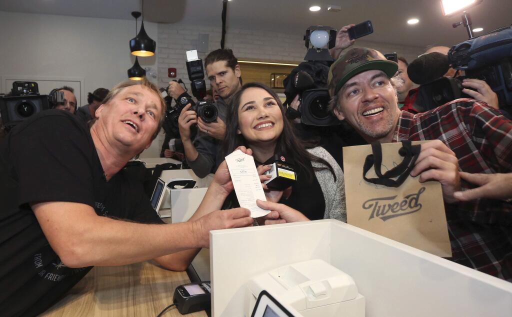 Canopy Growth CEO Bruce Linton, left to right, poses with the receipt for the first legal cannabis for recreation use sold in Canada to Nikki Rose and Ian Power at the Tweed shop on Water Street in St. John's N.L. at 12:01 am NDT on Wednesday Oct. 17, 2018. (Paul Daly/The Canadian Press via AP)
