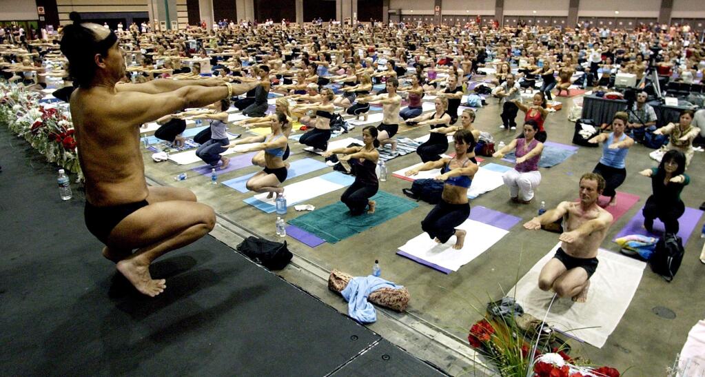 FILE - This Sept. 27, 2003 file photo Bikram Choudhury, front, founder of the Yoga College of India and creator and producer of Yoga Expo 2003, leads a yoga class at the Expo at the Los Angeles Convention Center. A half-dozen women claim Choudhury, the founder of the popular hot yoga studios that bear his name groped, harassed or sexually assaulted them. The most recent case filed this month claims that Choudhury raped a former student in 2010. (AP Photo/Reed Saxon,File)