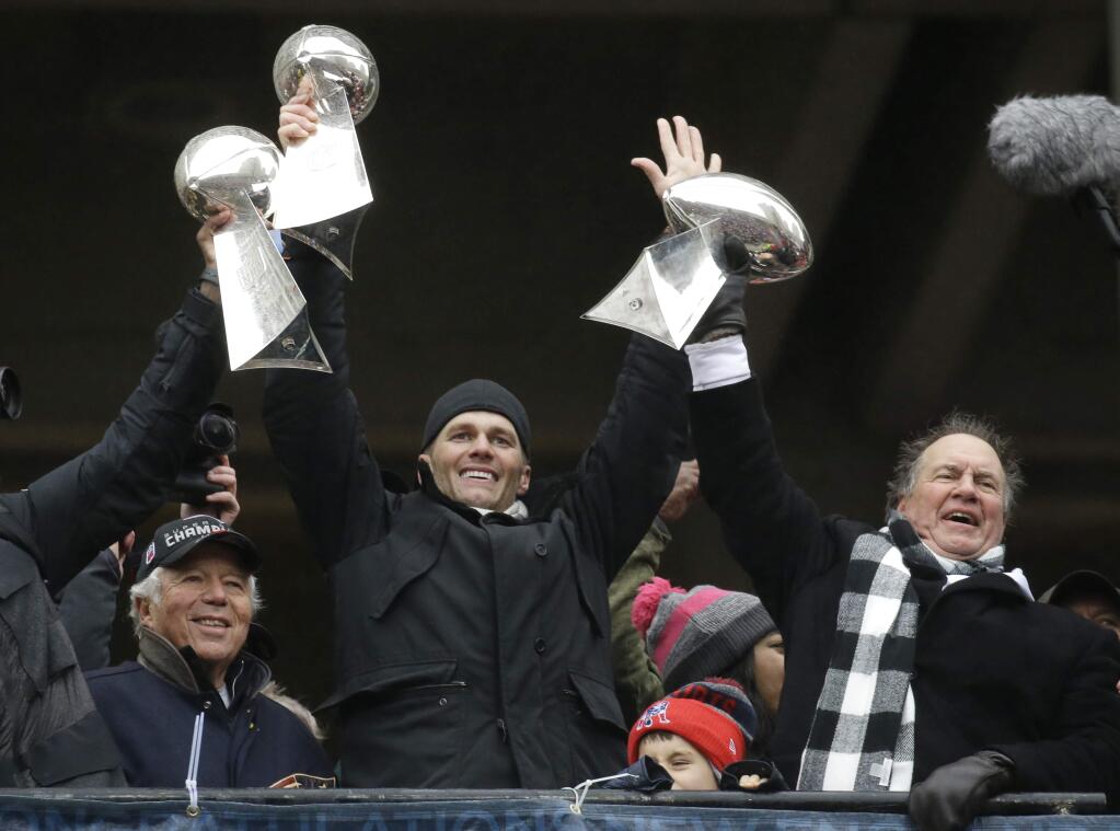 In this Feb. 7, 2017, file photo, New England Patriots quarterback Tom Brady holds up a Super Bowl trophy along with head coach Bill Belichick, right, and team owner Robert Kraft, left, during a rally in Boston to celebrate a 34-28 win over the Atlanta Falcons in the Super Bowl in Houston. (AP Photo/Elise Amendola, File)