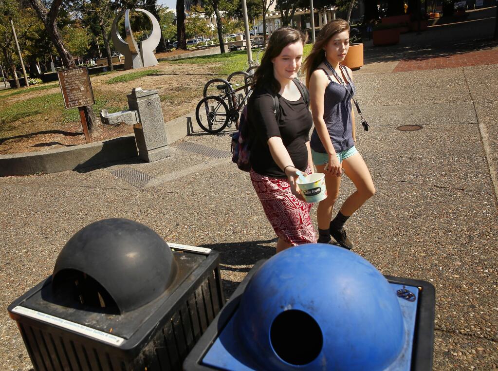 Dakota Blackstone, left, throws away her trash in the receptacles along Courthouse Square in Santa Rosa on Friday, September 5, 2014. Surrounding businesses have complained about weeds and garbage littering the square affecting their business. (Conner Jay/The Press Democrat)