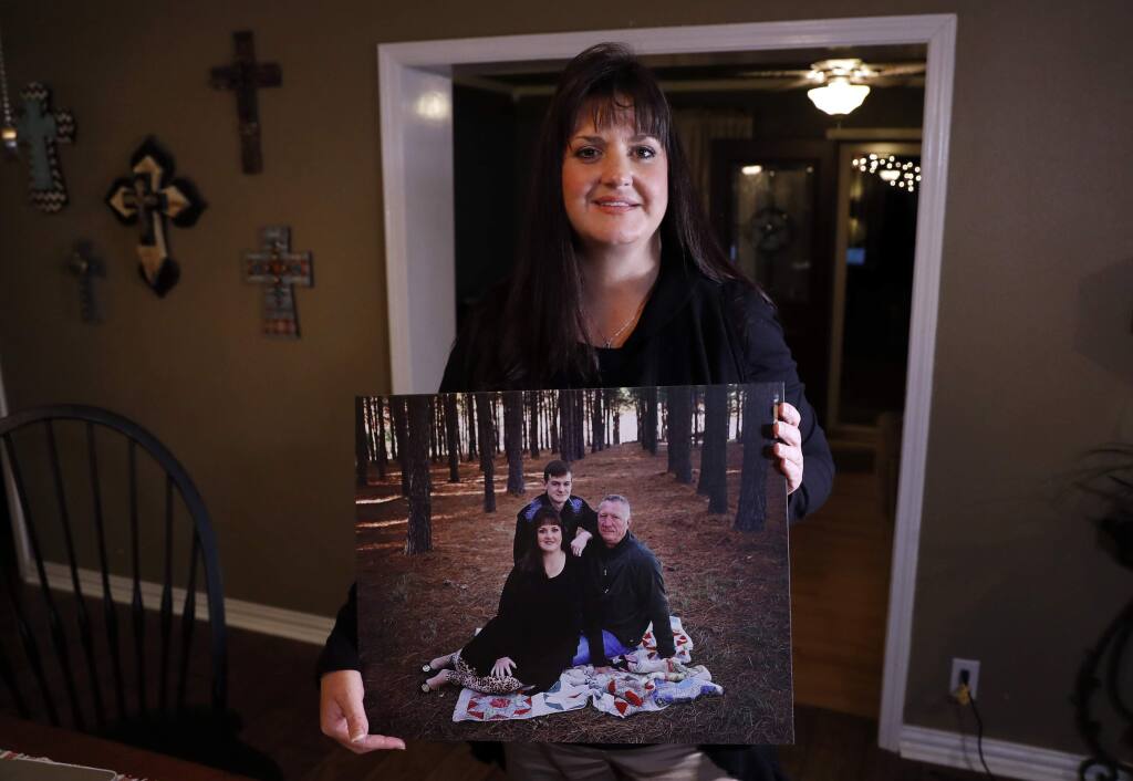 In this Thursday, Dec. 20, 2018 photo, Reagen Adair poses for a photo at her home holding a portrait of herself, with her husband Dale and son Mason, in Murchison, Texas. Adair, a fifth-grade teacher, had $3,100 in debt erased by RIP Medical Debt. The co-founders of RIP buy millions of dollars in past-due medical debt for pennies on the dollar. (AP Photo/Tony Gutierrez)