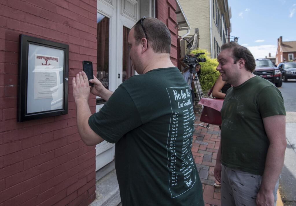 Brandon Hintze, left, of Alexandria, Va., and Brian Tayback, of Shrewsbury, Pa., take a photo of the menu outside of the Red Hen Restaurant, Saturday, June 23, 2018, in Lexington, Va. White House press secretary Sarah Huckabee Sanders said Saturday in a tweet that she was booted from the Virginia restaurant because she works for President Donald Trump. Sanders said she was told by the owner of The Red Hen that she had to 'leave because I work for @POTUS and I politely left.' (AP Photo/Daniel Lin)