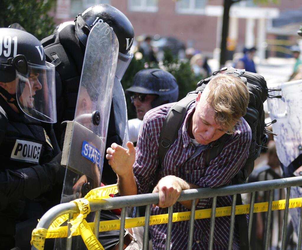 An white nationalist demonstrator is pushed out of the park by police at the entrance to Lee Park in Charlottesville, Va., Saturday, Aug. 12, 2017. Gov. Terry McAuliffe declared a state of emergency and police dressed in riot gear ordered people to disperse after chaotic violent clashes between white nationalists and counter protestors. (AP Photo/Steve Helber)