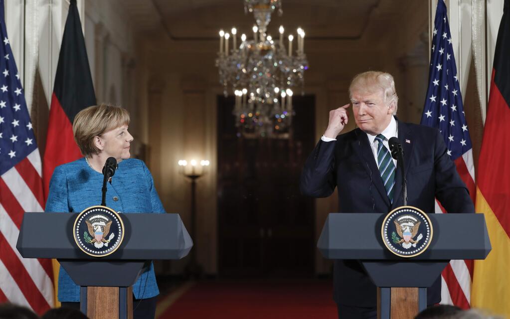 President Donald Trump points to his ear piece as he waits to listen for the translation while participating in a joint news conference with German Chancellor Angela Merkel in the East Room of the White House in Washington, Friday, March 17, 2017. (AP Photo/Pablo Martinez Monsivais)