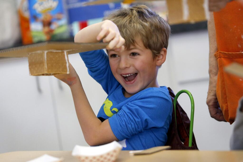 Anders Smith, 6, gets excited after realizing his gingerbread house is stuck to a board and can be flipped upside down during a winter workshop at the Children's Museum of Sonoma County in Santa Rosa, on Wednesday, December 23, 2015. (BETH SCHLANKER/ The Press Democrat)