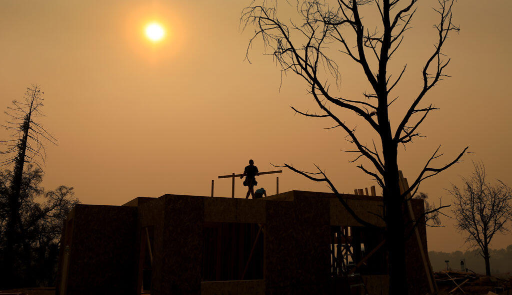 Tsiyani Escort, left, and Greg Pettegrew work on a home that was razed during the 2017 Tubbs fire on Fairway Knoll Court in Santa Rosa’s Fountaingrove, as the skies are mired in smoke from the Camp fire in Butte County, Thursday, Oct. 8, 2018. (Kent Porter / The Press Democrat) 2018