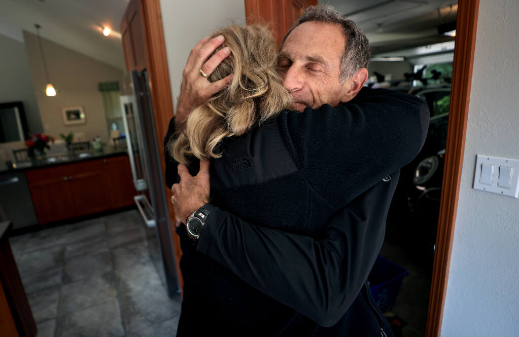 Barely in the doorway, Tuesday, April 19, 2022 , David Schneider is embraced by his wife Dana, as he arrives home from a three-week humanitarian mission to Poland, helping Ukrainian refugees who crossed the border who were in need of luggage and transportation to store their belongings. (Kent Porter / The Press Democrat) 2022