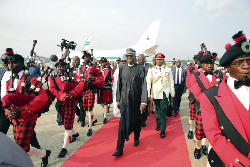 FILE - In this Aug. 19, 2017, file photo released by the Nigeria State House, Nigeria's President Muhammadu Buhari, center, walks upon his arrival at the airport in Abuja, Nigeria, after returning from more than three months in London for medical treatment. The coronavirus pandemic could narrow one gaping inequality in Africa, where some heads of state and other elite jet off to Europe or Asia for health care unavailable in their nations but as global travel restrictions tighten, they might have to take their chances at home. (Sunday Aghaeze/Nigeria State House via AP, File)
