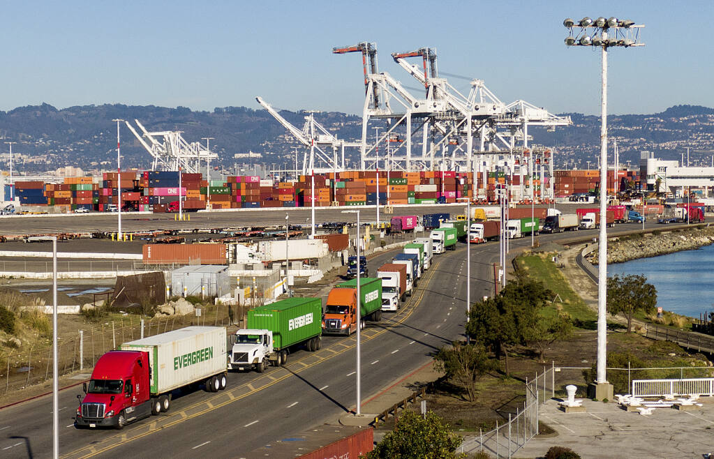 FILE — Trucks line up to enter a Port of Oakland shipping terminal on Nov. 10, 2021, in Oakland, Calif. Intense demand for products has led to a backlog of container ships outside the nation's two largest ports along the Southern California coast. (AP Photo/Noah Berger, File)