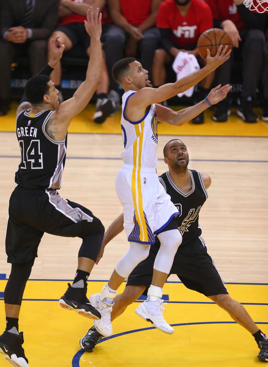 Golden State Warriors guard Stephen Curry goes to the basket between San Antonio Spurs defenders Danny Green and Tony Parker during their game in Oakland on Monday, Jan. 25, 2016. (Christopher Chung / The Press Democrat)