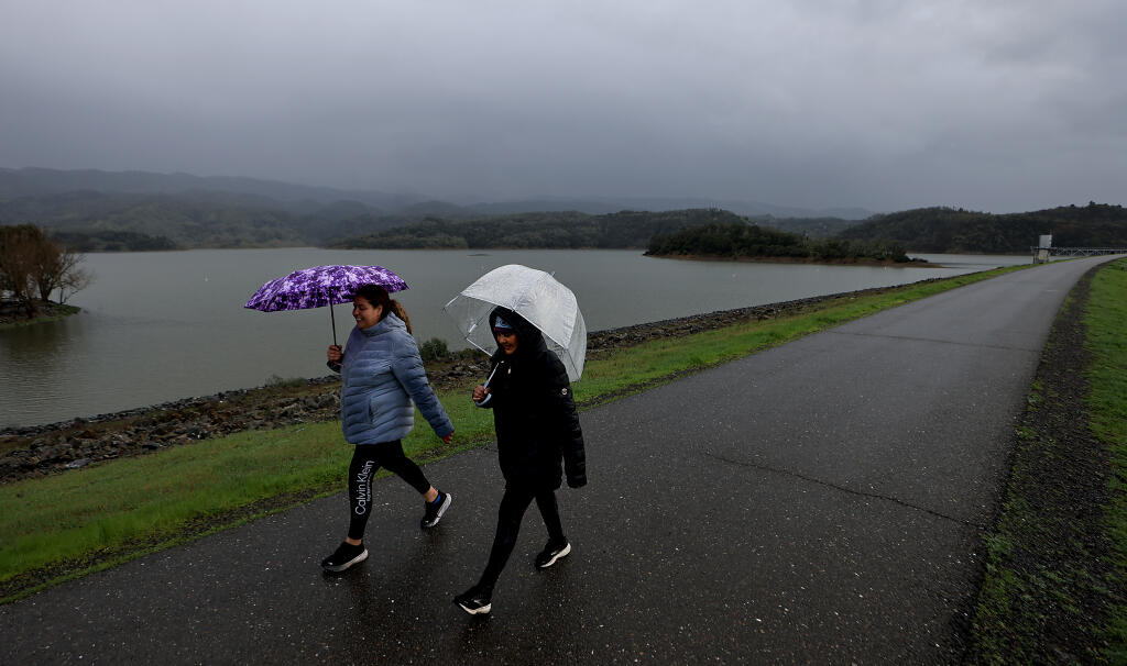 Ukiah residents Jovanna Corona, left, and Celia Rivera, take advantage of a break in the weather for a walk along the Coyote Valley Dam, Thursday, Feb. 1, 2024 as Lake Mendocino continues to rise with the ongoing storms. (Kent Porter / The Press Democrat)