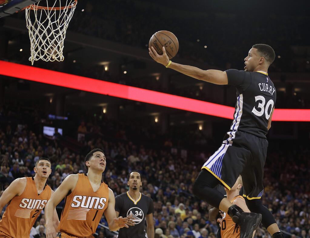 Golden State Warriors' Stephen Curry (30) lays up a shot against Phoenix Suns' Eric Bledsoe, left, and Devin Booker (1) during the first half Saturday, March 12, 2016, in Oakland. (AP Photo/Ben Margot)