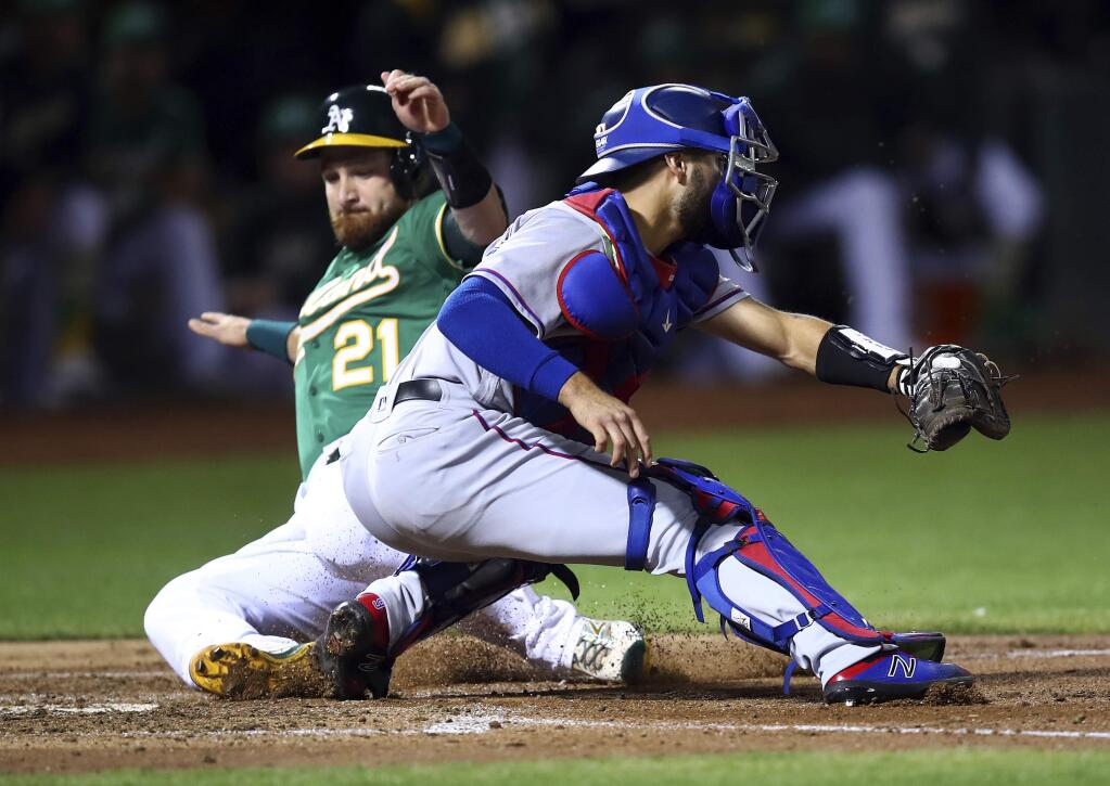 Texas Rangers catcher Isiah Kiner-Falefa, right, waits for the ball as Oakland Athletics' Jonathan Lucroy (21) slides to score in the second inning of a baseball game Friday, Sept. 7, 2018, in Oakland, Calif. (AP Photo/Ben Margot)