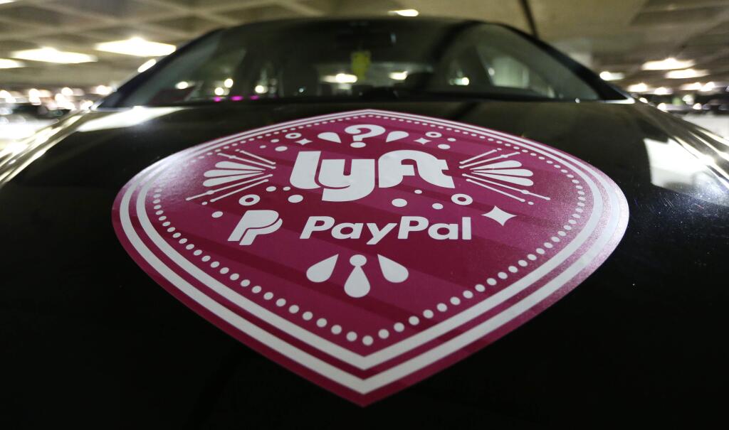 FILE - In this March 31, 2016, a Lyft ride-hailing service logo is displayed on a vehicle at Seattle-Tacoma International Airport in Seattle. Lyft is setting up its own unit to develop autonomous vehicle technology, but its approach will be different from other companies and partnerships working on self-driving cars. The San Francisco-based ride-hailing service says it will open its network, inviting automakers and tech companies to use it to haul passengers and gather data. . (AP Photo/Ted S. Warren, File)