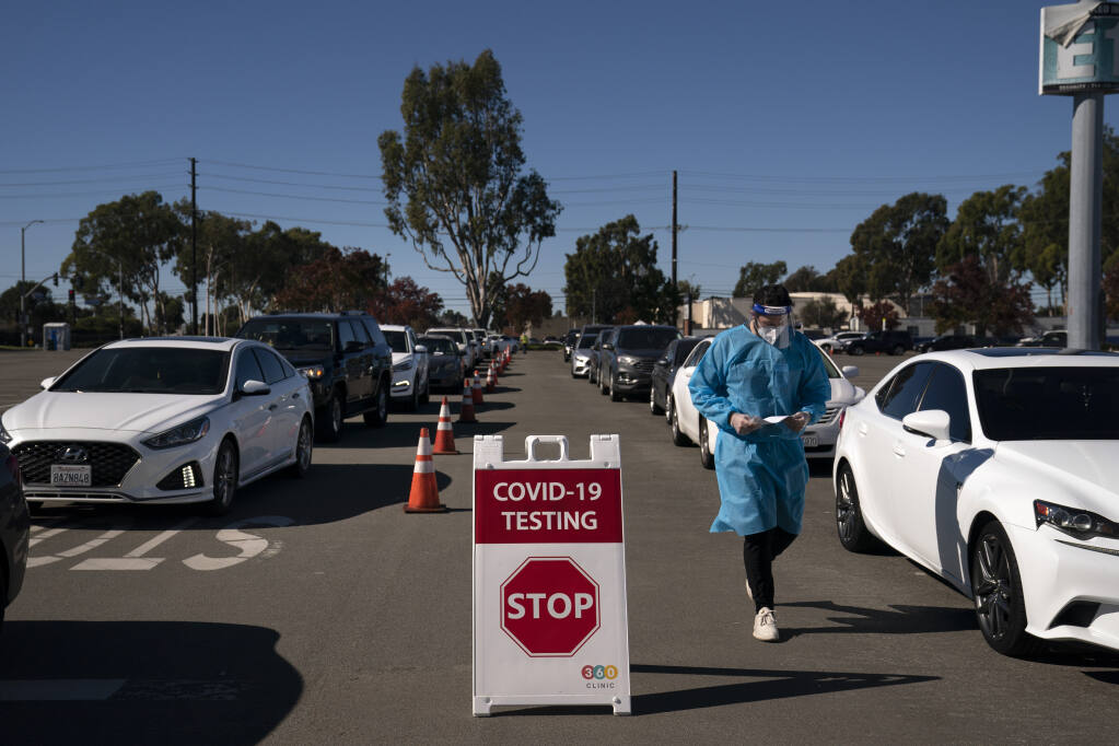 Student nurse Ryan Eachus collects forms as cars line up for COVID-19 testing at a testing site set up the Orange County Fairgrounds in Costa Mesa on Nov. 16, 2020. (Jae C. Hong, / Associated Press)