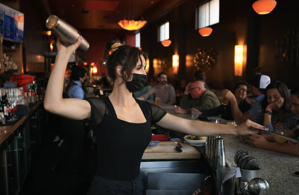 Jackson's Bar and Oven bartender Jaycie Mariani mixes a drink while handing out a menu during the evening dinner rush, Friday, Sept. 17, 2021 in Santa Rosa.   (Kent Porter / The Press Democrat) 2021