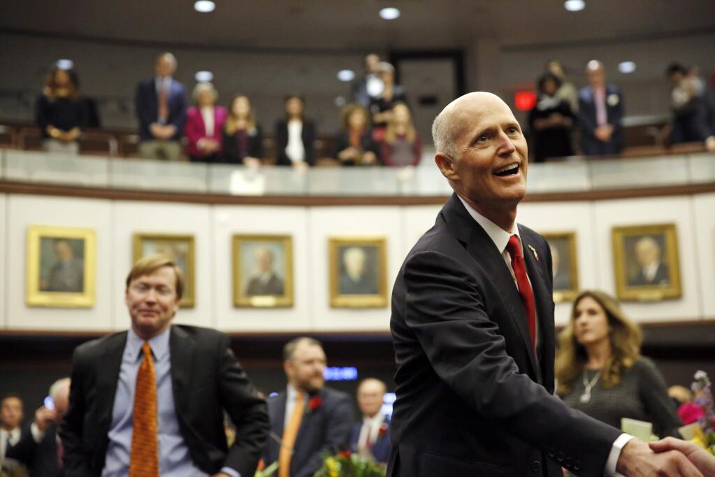 Florida Gov. Rick Scott is greeted in the Senate chambers on the opening day of the legislative session, Tuesday, Jan. 9, 2018, in Tallahassee, Fla. (Hali Tauxe/Tallahassee Democrat via AP)