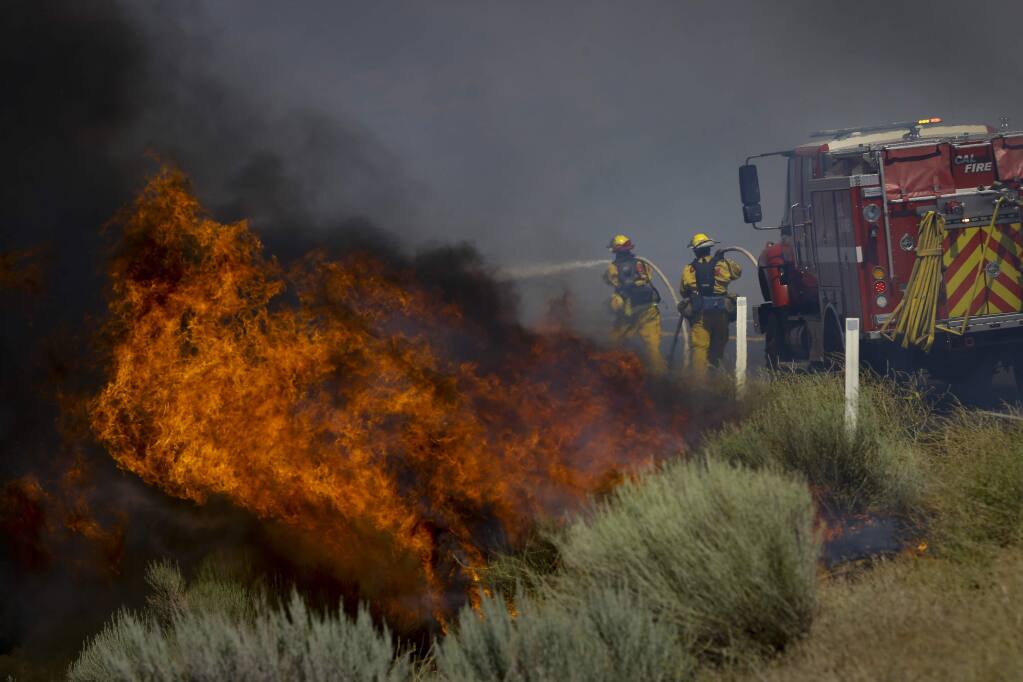 Firefighters battle a wildfire burning along Highway 178 near Lake Isabella, Calif., Friday, June 24, 2016. The wildfire that roared across dry brush and trees in the mountains of central California gave residents little time to flee as flames burned homes to the ground, propane tanks exploded and smoke obscured the path to safety. (AP Photo/Jae C. Hong)
