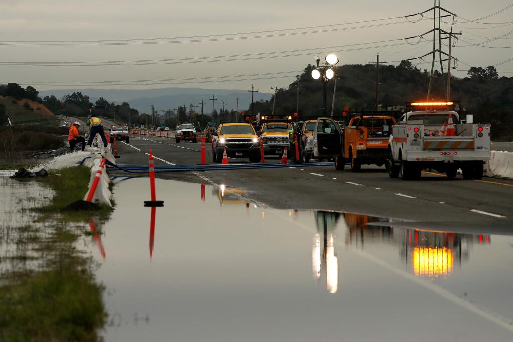 Workers from Caltrans and Ghilotti Brothers construction check road conditions and pump flood water away from Highway 37 after a levee along Novato Creek was broken, flooding the highway near Novato, California, on Friday, March 1, 2019. (Alvin Jornada / The Press Democrat)