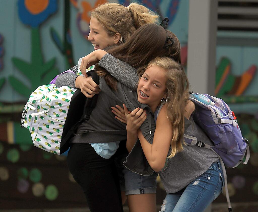 Eighth graders Piper Buchignani, Savannah Hines and Anya Fouts greet one another prior to the start of the first day of school at Santa Rosa Charter School for the Arts, Tuesday August 15, 2017 in Santa Rosa. (Kent Porter / The Press Democrat) 2017