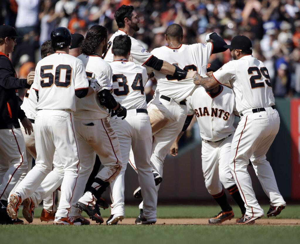 San Francisco Giants' Justin Maxwell, center, is mobbed by teammates after driving in the game-winning run against the Los Angeles Dodgers during the 10th inning on Thursday, April 23, 2015, in San Francisco. San Francisco won 3-2. (AP Photo/Marcio Jose Sanchez)