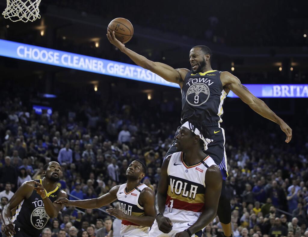 Golden State Warriors' Andre Iguodala (9) lays up a shot over New Orleans Pelicans' Jrue Holiday (11) during the second half of an NBA basketball game Wednesday, Jan. 16, 2019, in Oakland, Calif. (AP Photo/Ben Margot)