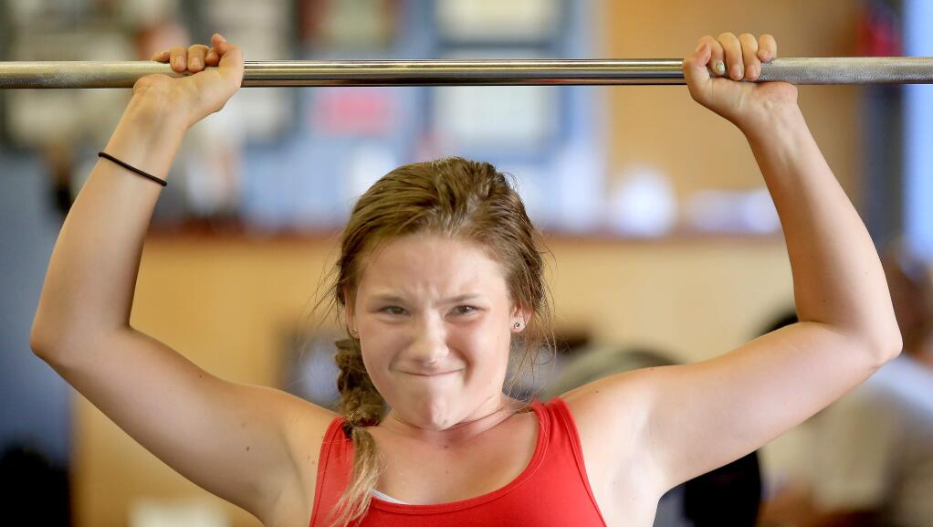 At the tail end of her workout, Athena Schrijver, 13, struggles to push weight over her head, Thursday June 26, 2014 at Myles Ahead Weightlifting in Petaluma. (Kent Porter / Press Democrat) 2014