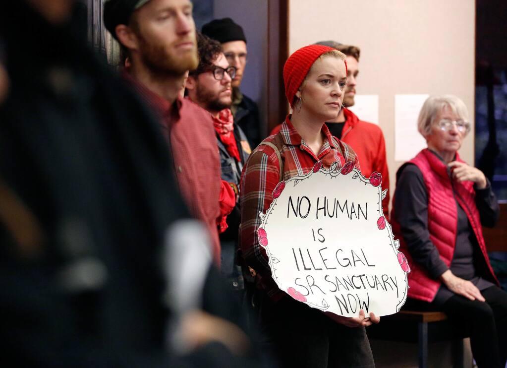 Quenby Dolgushkin holds a sign in support of making Santa Rosa a sanctuary city during a city council meeting to discuss a proposal giving safe haven to undocumented immigrants in Santa Rosa, California on Tuesday, Feb. 7, 2017. (Alvin Jornada / The Press Democrat)
