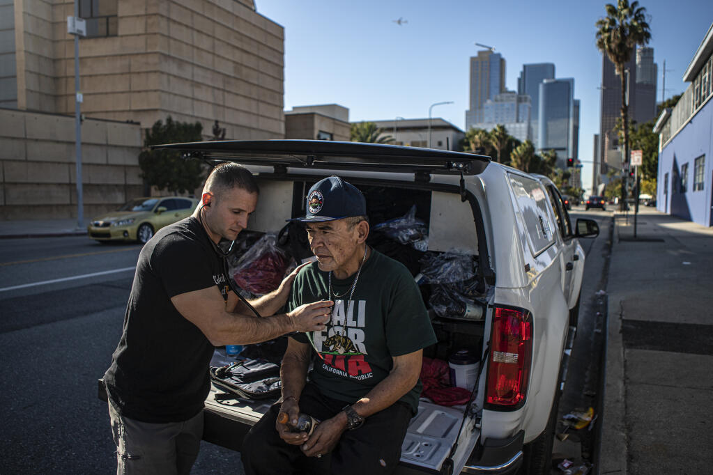 Physician's assistant Brett Feldman does a checkup on his patient Gary Dela Cruz on the side of the road near his encampment in downtown Los Angeles on Nov. 18, 2022. Feldman is the director and co-founder of Street Medicine at the Keck School of Medicine at the University of Southern California.Photo by Larry Valenzuela for CalMatters