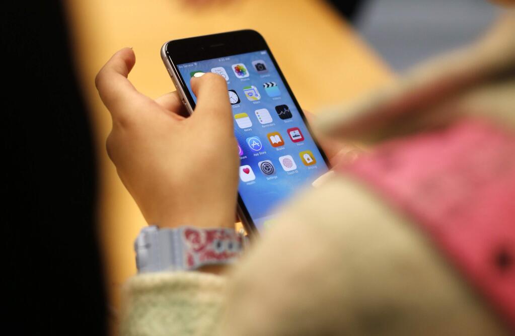 FILE - In this Sept. 25, 2015, file photo, a child holds an Apple iPhone 6S at an Apple store on Chicago's Magnificent Mile in Chicago. The World Health Organization Wednesday, April 24, 2019, issued its first-ever guidance for how much screen time children under 5 should get: not very much, and none at all for those under 1. (AP Photo/Kiichiro Sato, File)