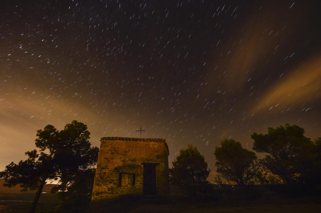 Stars seen as streaks from a long camera exposure are seen behind Arnotegui Hermitage, in Obanos, northern Spain, Tuesday, Aug. 11, 2015. Some Catholics refer to the Perseids as the 'tears of Saint Lawrence', since 10 August is the date of that saint's martyrdom. (AP Photo/Alvaro Barrientos)