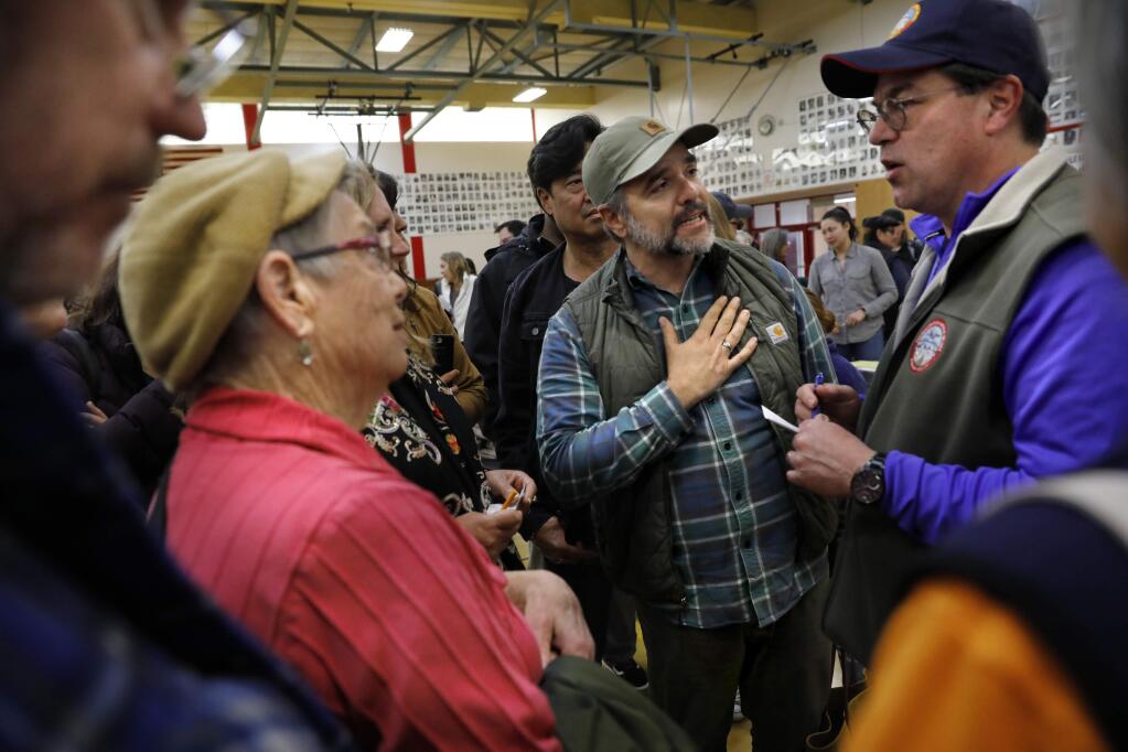 Westside Ave. resident Brian Andriola, center, tries to express his concerns to Johannes Hoevertsz, right, the director of County of Sonoma Department of Transportation and Public Works, about a landslide affecting his street and neighborhood during a flood recovery community meeting at El Molino High School in Forestville, California on Sunday, March 3, 2019 . (BETH SCHLANKER/The Press Democrat)