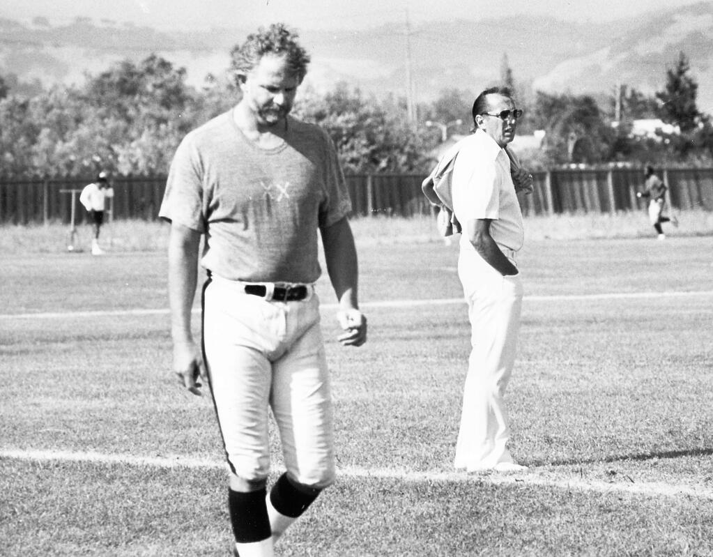 Raiders owner Al Davis, right, stands on the field at El Rancho Tropicana Hotel complex as an unidentified player walks by.