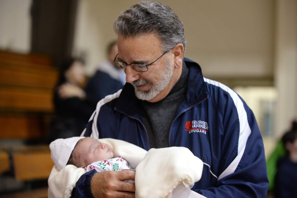 Rancho Cotate boys basketball coach Dennis Magatelli spent a few brief moments with his 8-day-old grandson Giovanni Bianchini before the start of a December 2014 game. (Erik Castro / for The Press Democrat)