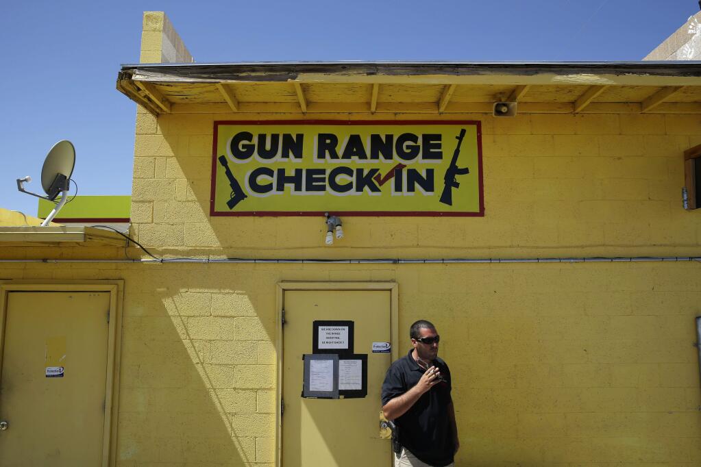 An employee smokes outside of an office for the Last Stop outdoor shooting range Wednesday, Aug. 27, 2014, in White Hills, Ariz. (AP Photo/John Locher)