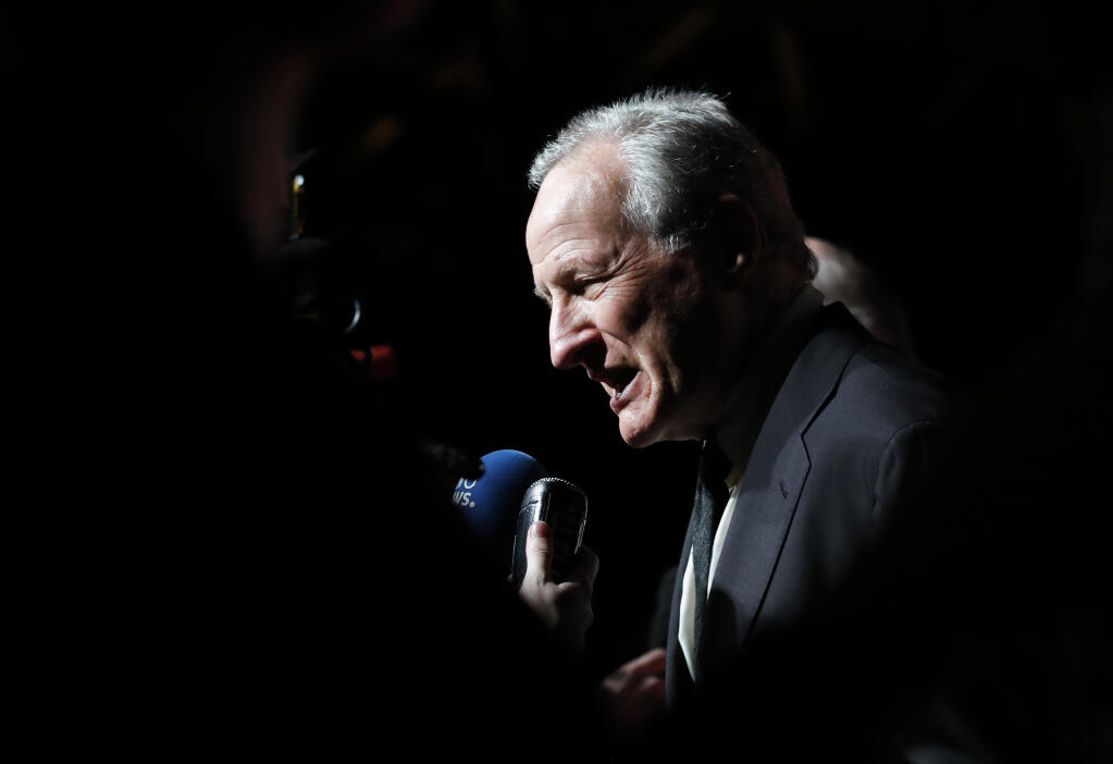 FILE - Director Michael Mann answers questions as he arrives for the opening ceremony of the ninth Lumiere Festival, in Lyon, central France, Oct. 14, 2017. Mann has co-written a novel that revisits the characters of his 1995 film "Heat" in both prequel and sequel fashion, filling in the backstory and what happened to characters played by Al Pacino, Robert De Niro and Val Kilmer. (AP Photo/Laurent Cipriani, File)