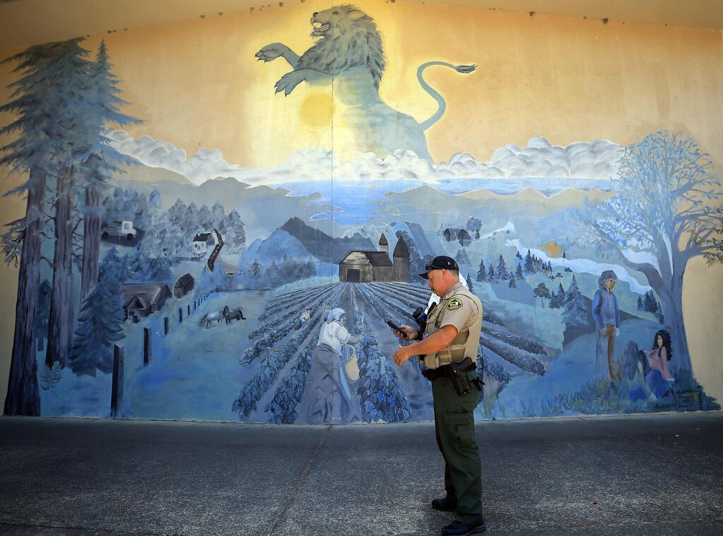 Mark Aldridge, a long time deputy with the Sonoma County Sheriff's Department, pauses while making his rounds as El Molino High School's new resource officer, Friday, August 23, 2019 in Forestville. The mural has been around since Aldridge graduated from the school in 1987. (Kent Porter / The Press Democrat) 2019