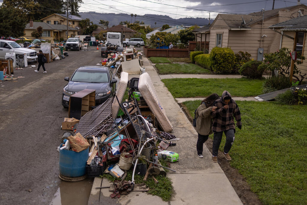 Local residents walk by damaged belongings after numerous rain storms known as "atmospheric river" flooded a residential area, in Pajaro March 29, 2023. Photo by Carlos Barria, REUTERS