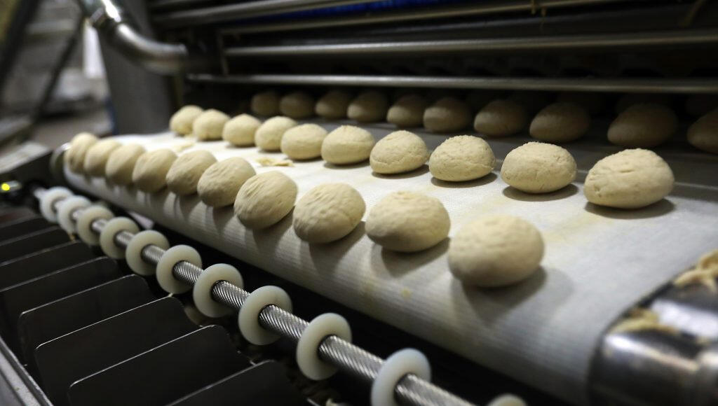Dough balls head down the line to be flattened into shape at the La Tortilla Factory in Santa Rosa. John Burgess/The Press Democrat