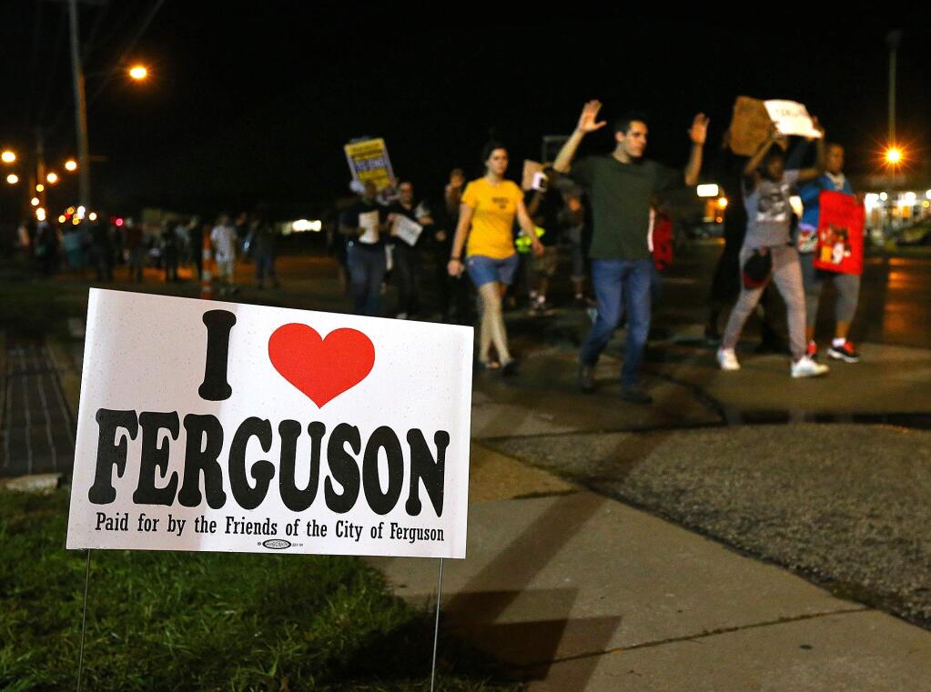 A small group of protesters marches down West Florissant Avenue in Ferguson, Mo. on Wednesday, Aug. 20, 2014. On Aug. 9, 2014, a white police officer fatally shot Michael Brown, an unarmed black 18-year old, in the St. Louis suburb. (AP Photo/Atlanta Journal-Constitution, Curtis Compton)