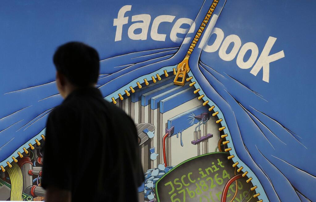 FILE - In this June 11, 2014, file photo, a man walks past a mural in an office on the Facebook campus in Menlo Park, Calif. The California Supreme Court will decide whether Facebook and other social media companies must turn over user content to criminal defendants. The justices are expected to rule Thursday, May 24, 2018, in a case that has pitted some of Silicon Valley's biggest companies against public defenders. (AP Photo/Jeff Chiu, File)