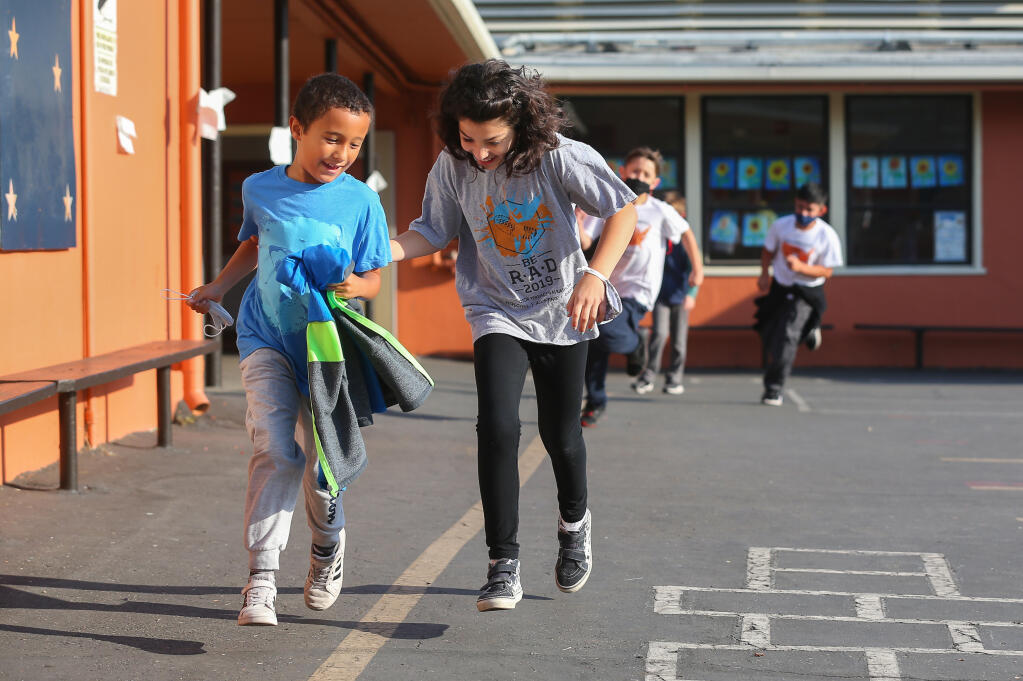 Third-graders Dylan Armanino, left, and Eliana Olvera race around the playground at Proctor Terrace Elementary School as part of the iDo26.2 running program in Santa Rosa on Friday, Sept. 24, 2021.  (Christopher Chung/ The Press Democrat)