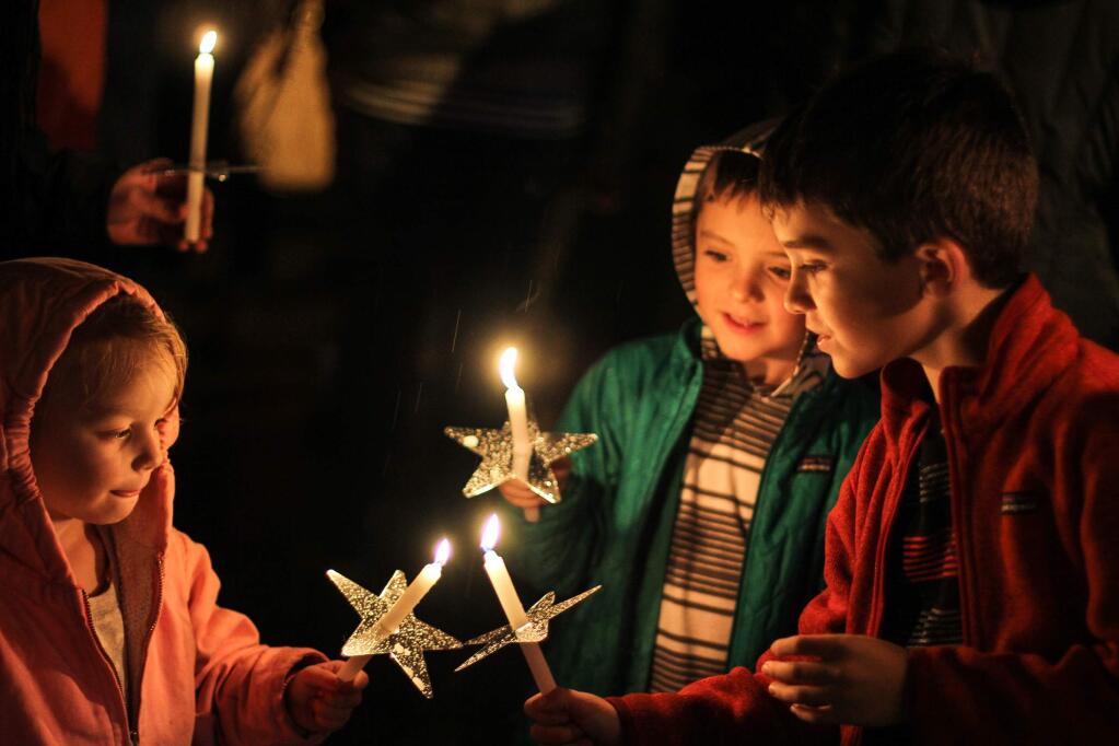 Trinity Gompper, Elias and Ethan Calcagno, light eachothers candles at the Light Up A Life tree lighting ceremony Hospice of Petaluma's annual community celebration of remembrance held in Center Park on Friday, December 5, 2014. (VICTORIA WEBB/FOR THE ARGUS-COURIER)