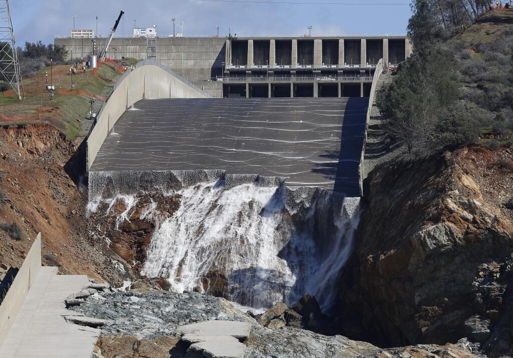 FILE - In this Feb. 28, 2017, file photo, water flows down the Oroville Dam's crippled spillway in Oroville, Calif. An independent team of dam experts says bad design and construction a half-century ago contributed to a disastrous spillway collapse at the nation's tallest dam. Dam-safety experts investigating February's spillway failures at the Oroville Dam say California should have assessed the original flaws. (AP Photo/Rich Pedroncelli, File)