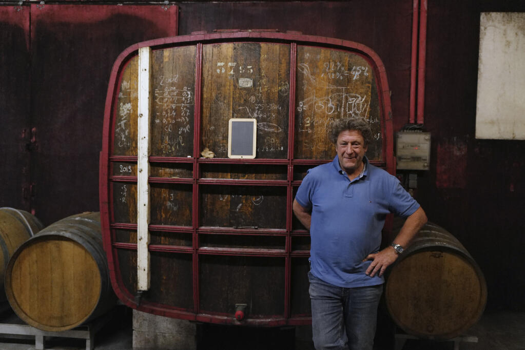 Champagne producer Anselme Selosse poses in front his 1974 first barrel in Avize, in the Champagne region, east of Paris, Tuesday, July 28, 2020. Producers in France’s eastern Champagne region, headquarters of the global industry, say they’ve lost about 1.7 billion euros ($2 billion) in sales this year, as turnover fell by a third —  a hammering unmatched in living memory, and worse than the Great Depression. (AP Photo/Francois Mori)