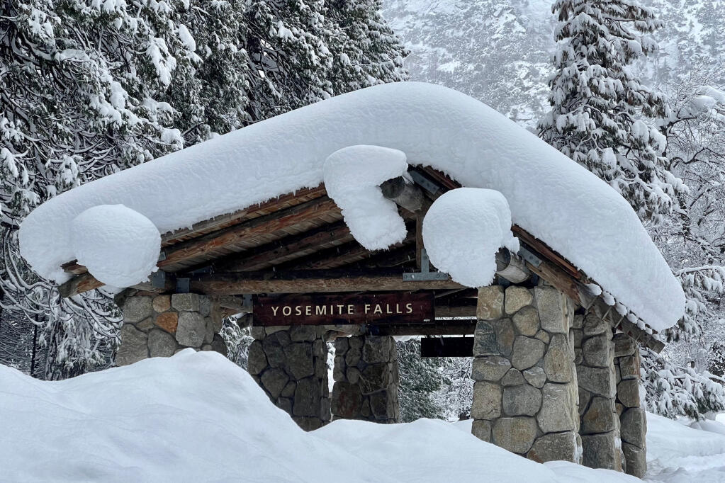 In this photo provided by the National Park Service, a structure at Yosemite Falls in Yosemite National Park, Calif., is covered in snow Tuesday, Feb. 28, 2023. Yosemite National Park, closed since Saturday because of heavy, blinding snow, postponed its planned Thursday, March 2, 2023, reopening indefinitely. (National Park Service via AP)
