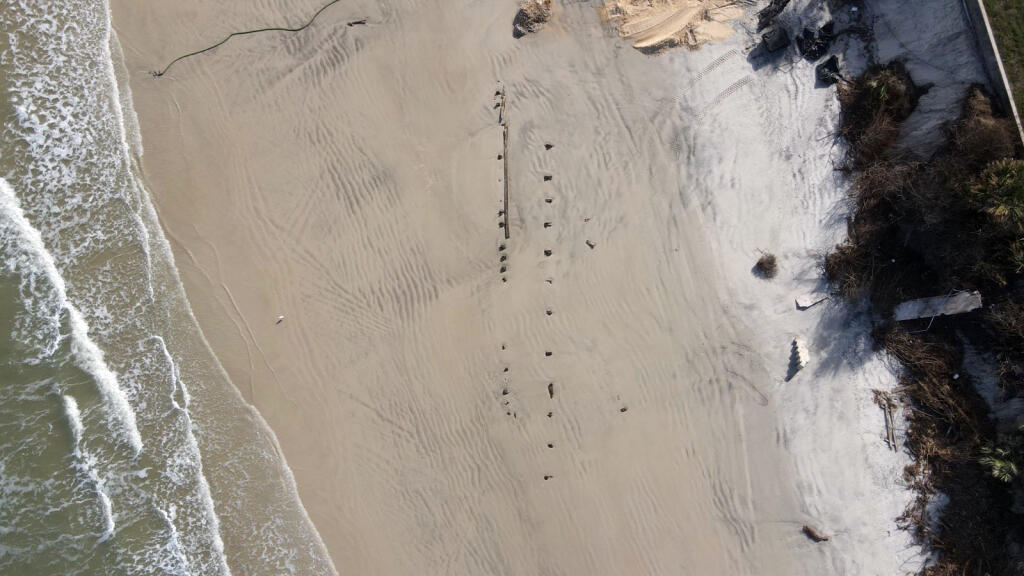 A photo provided by Volusia County, Fla., shows a mystery object protruding through the sand at Daytona Beach Shores. Some theories are that it is a barrier, a shipwreck, a portion of an old pier, or spectator seating from when NASCAR had races on the beach. (Volusia County via The New York Times)