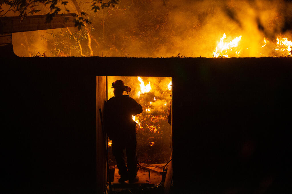 A firefighter stands watch beside a home on Adobe Canyon Road to make sure the house doesn't sustain damage during a defensive firing operation that began in Sugarloaf Ridge State Park to create a buffer between the head of the Glass fire and adjacent communities near Kenwood on Wednesday, Sept. 30, 2020. (Alvin A.H. Jornada / The Press Democrat)